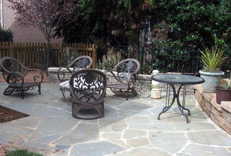 bluestone flagstone patio with a seating wall and outdoor furniture