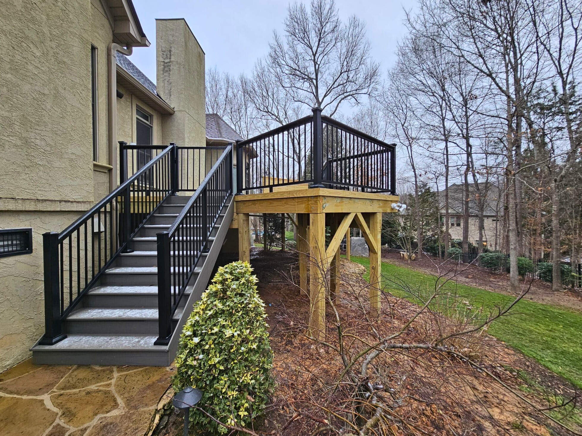 Multi-level Indian Land deck with black aluminum railings and custom stairs, leading to a flagstone patio below.