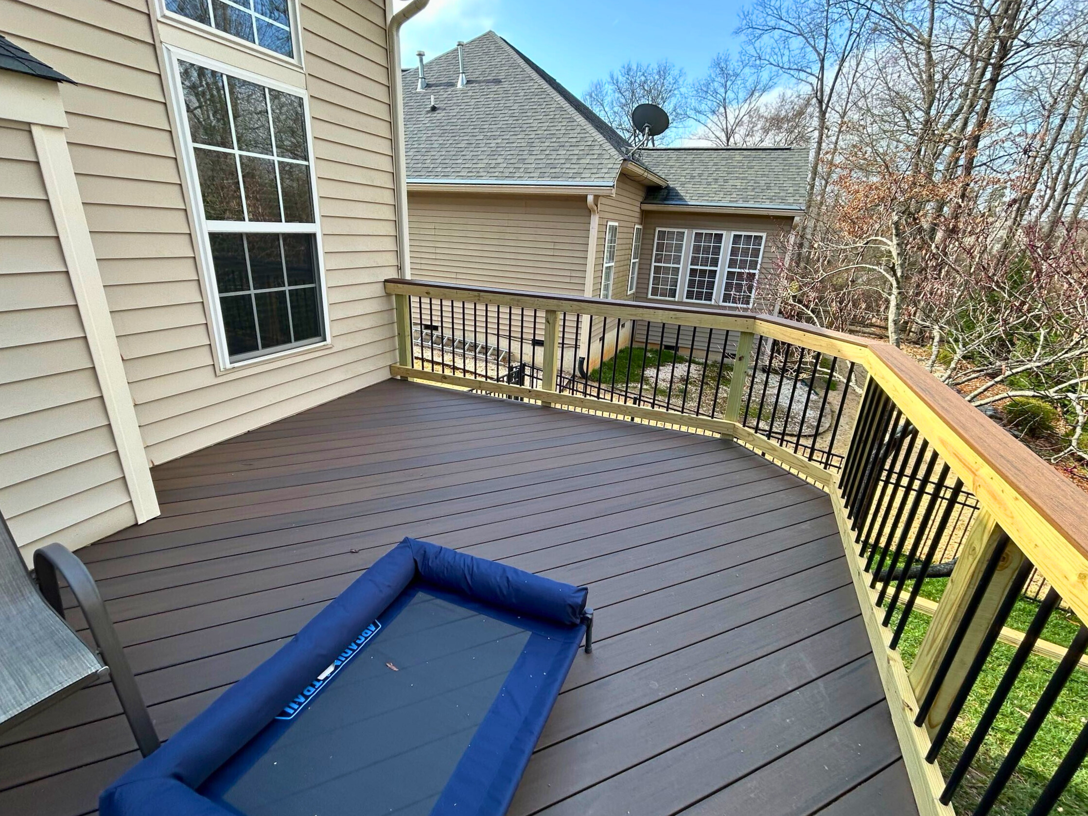 Two-toned Trex composite deck in Indian Land, SC, with black railing and natural wood handrail, offering a modern outdoor space.