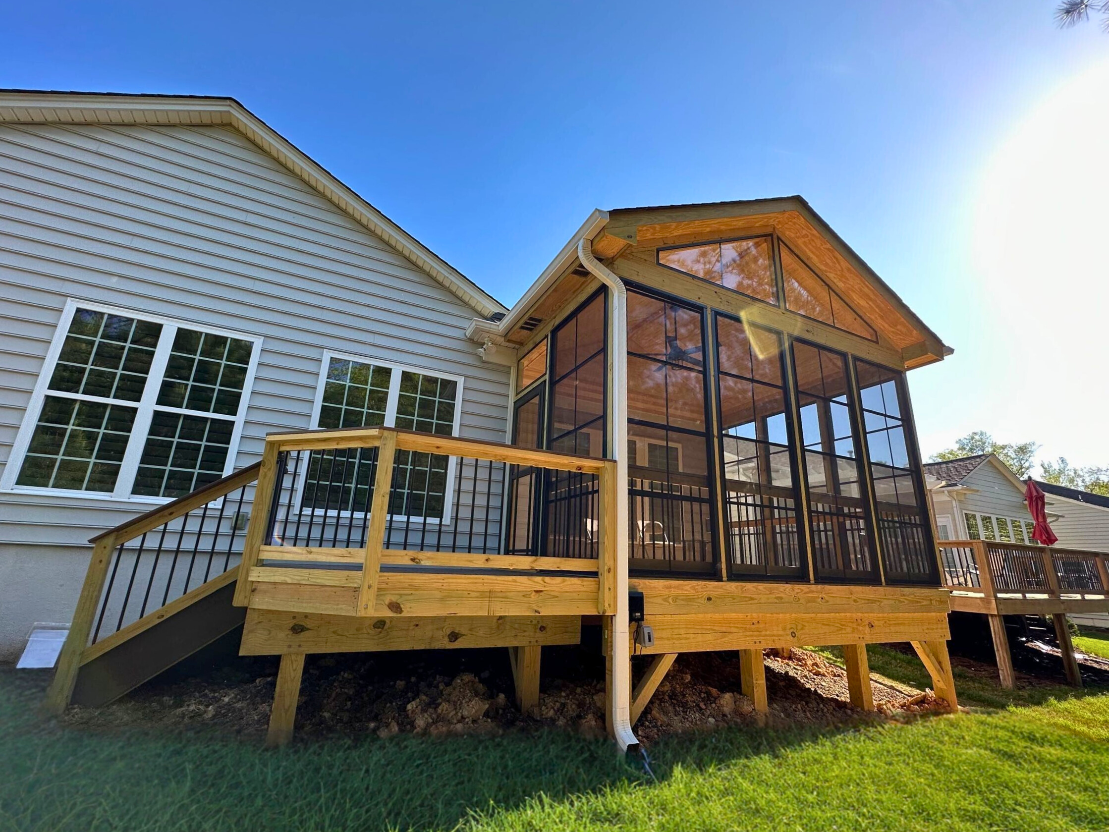 "Newly constructed Indian Land screened porch with a high vaulted ceiling and an adjacent wooden deck, ready for relaxation.