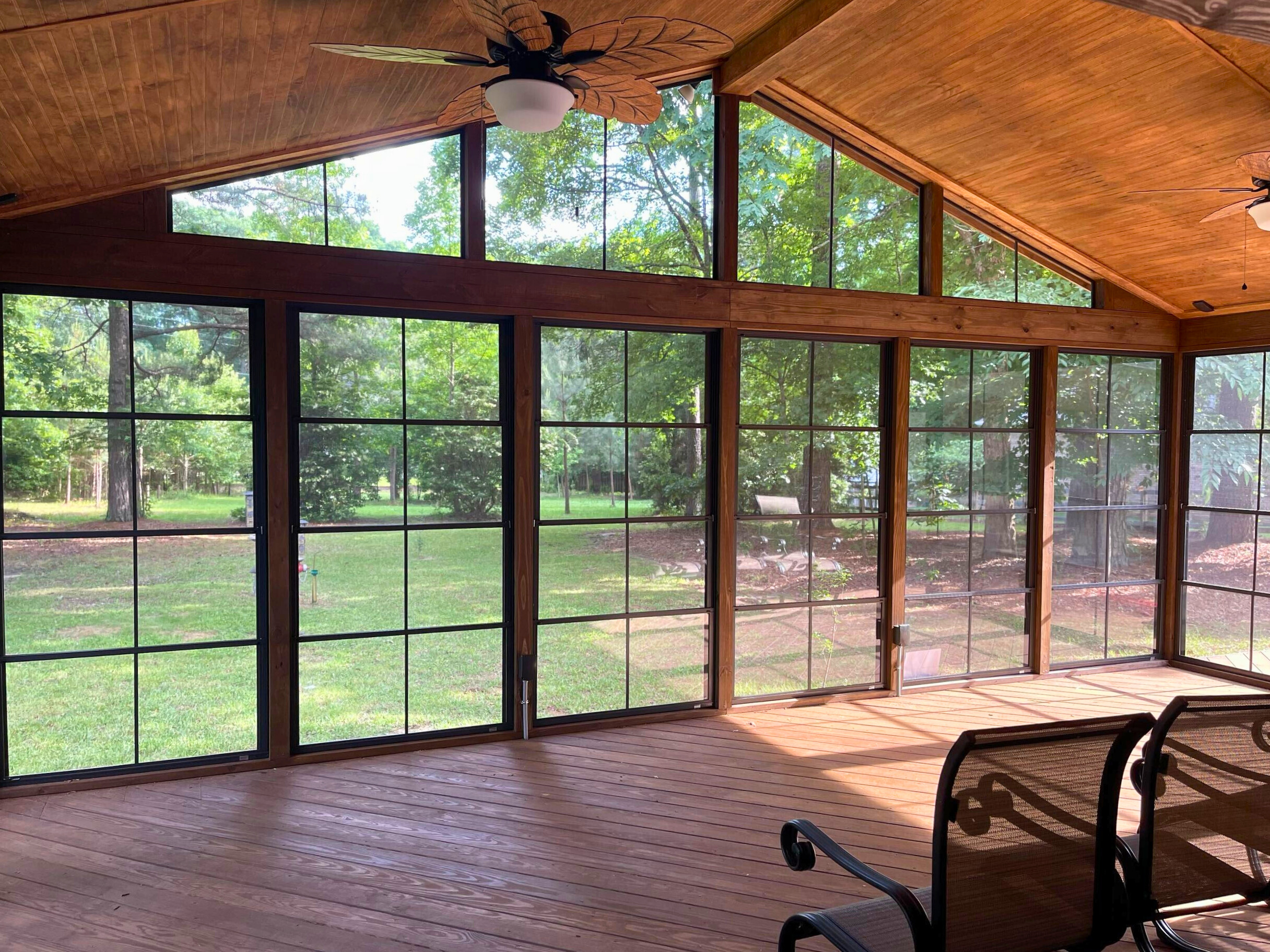 Interior of a large 3-season room in Matthews, NC, featuring a high, vaulted wooden ceiling, large windows, and a ceiling fan.