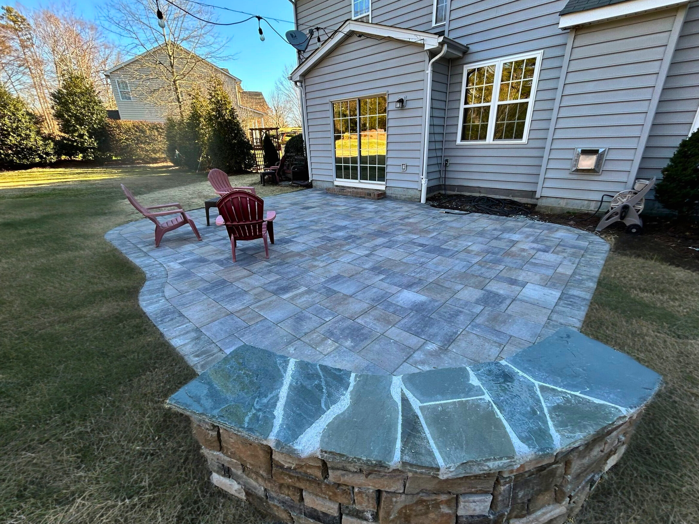 Interlocking paver patio installation with stone retaining wall by Archadeck, a trusted patio builder in Waxhaw, NC.