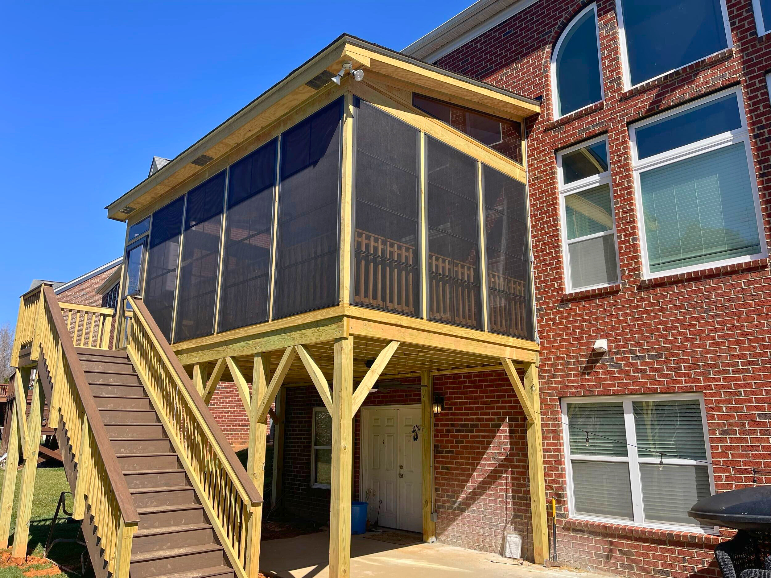 Elevated screened porch addition with wood stairs and vertical screening, constructed by Archadeck in Waxhaw, NC.