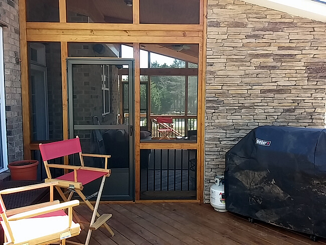 screened porch with chairs and barbecue