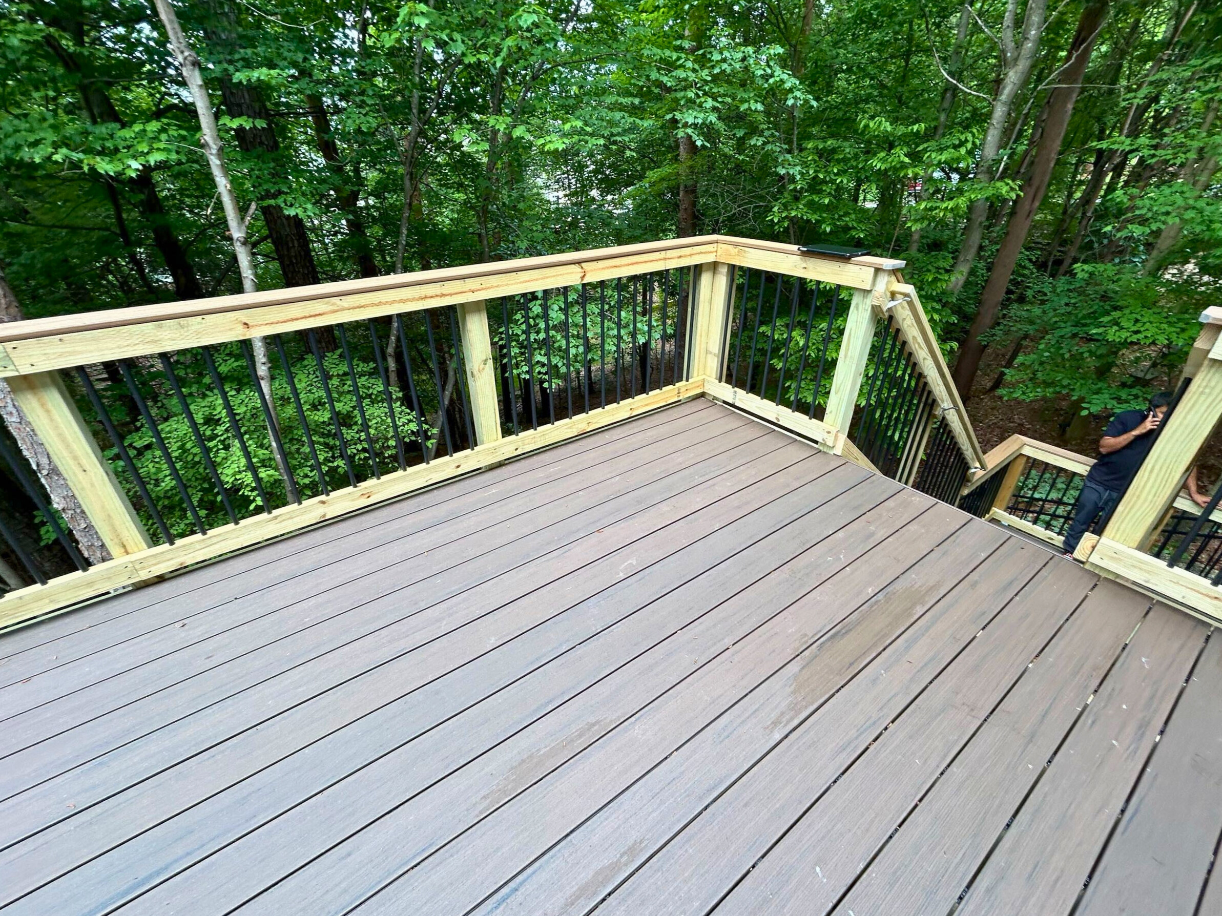 Multi-level Trex composite deck with black railings in a wooded Tega Cay backyard
