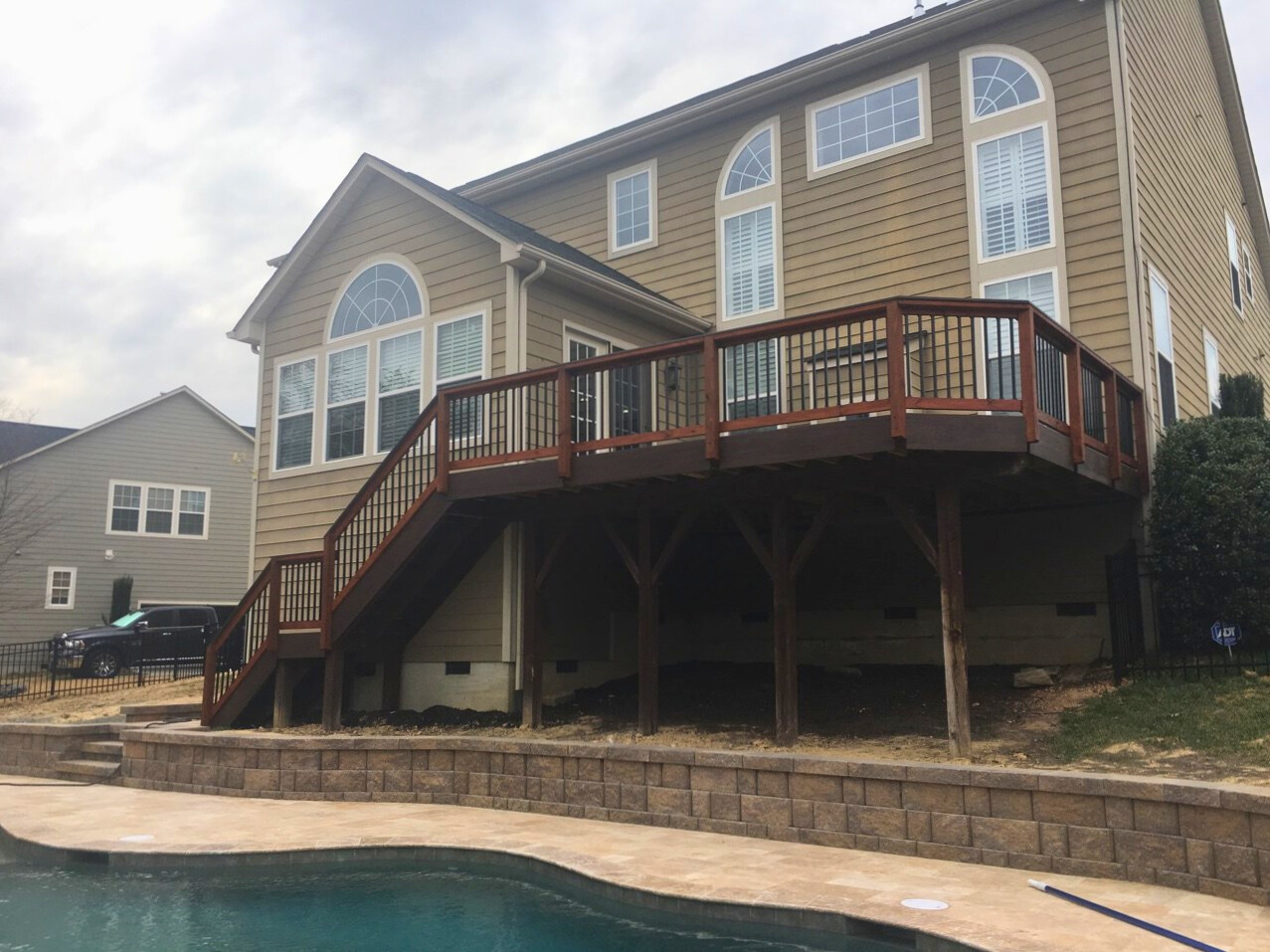 Elevated composite deck with stairs leading to a poolside patio, built in Tega Cay