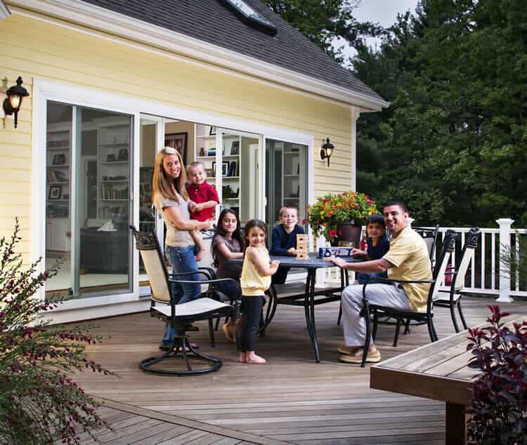 two adults and five kids sitting around a table on their deck
