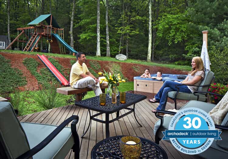 Family of four hanging out on their deck, graphic logo says, Charlotte's Outdoor Living Expert 30 Years, Better Building by Design