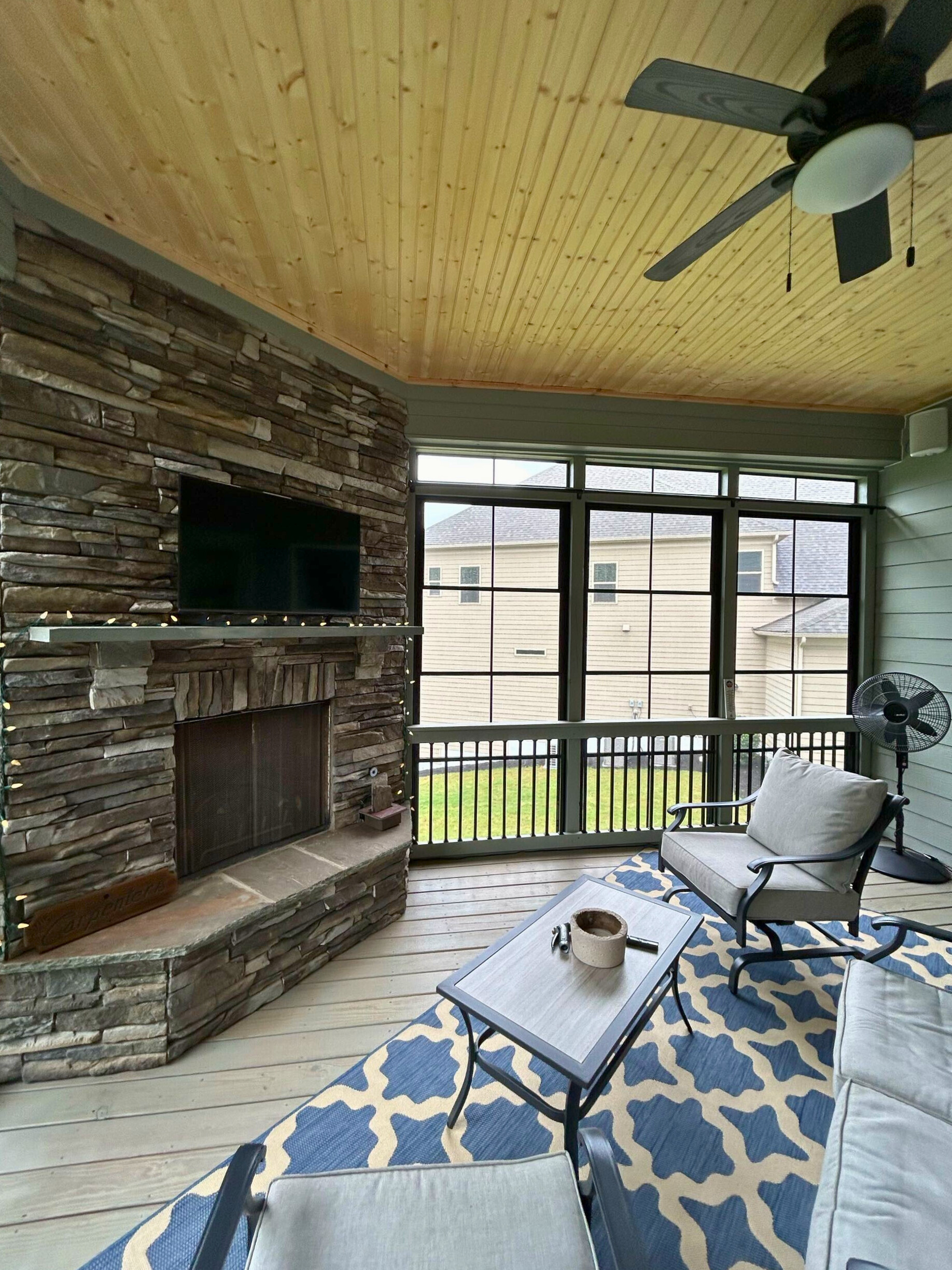 Cozy three-season room with a corner fireplace, offering extended outdoor living in Fort Mill, designed by a local builder.