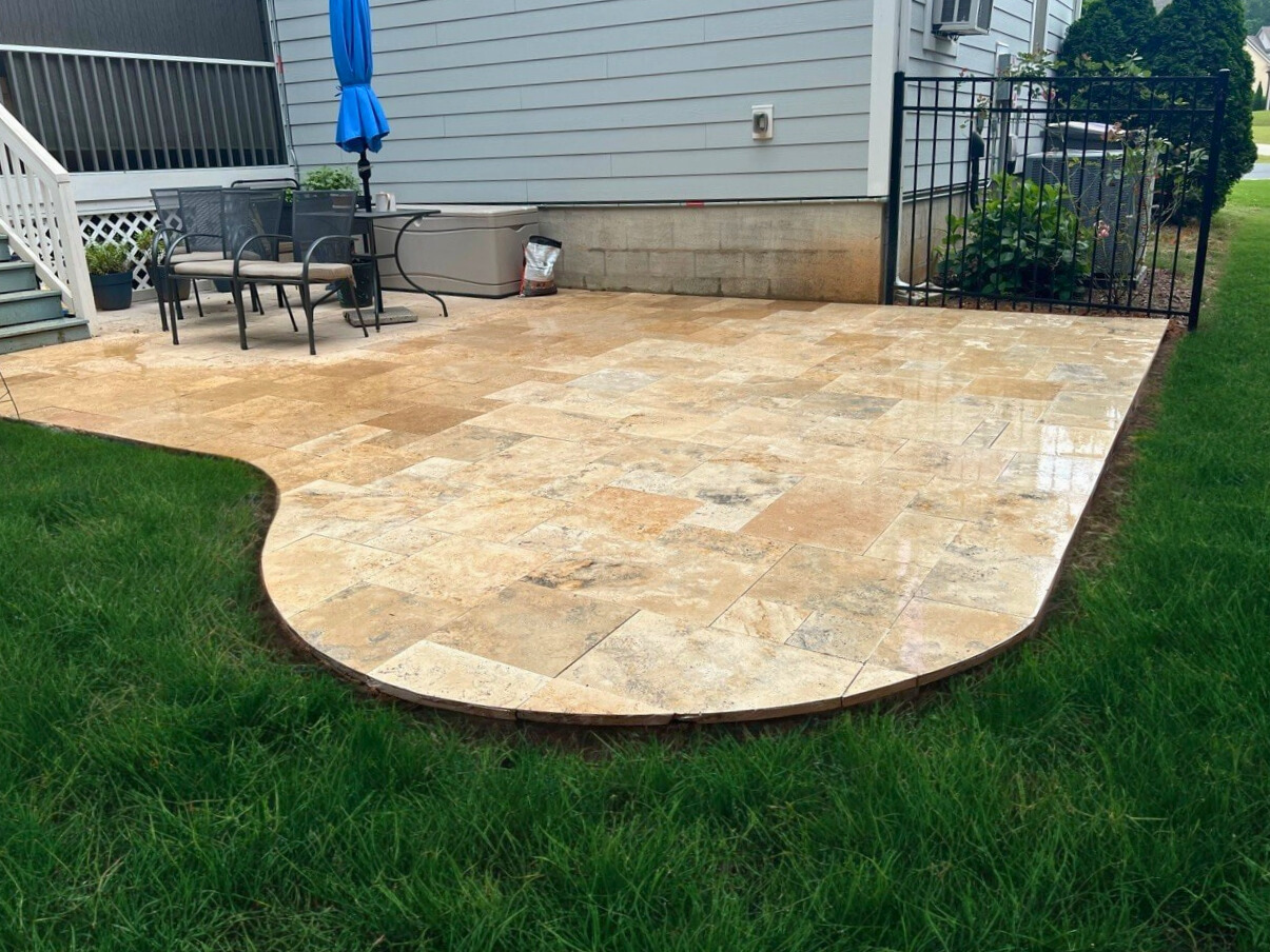 Custom Travertine tile patio with curved edge, installed by Archadeck for a Waxhaw, NC home.