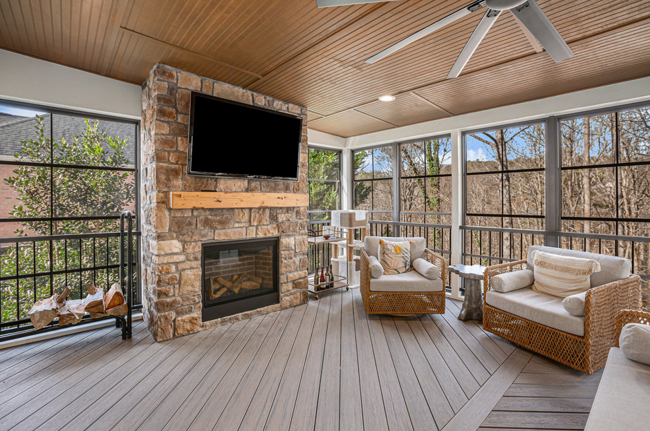 custom screened in porch with patio furniture and a mounted television on the fireplace