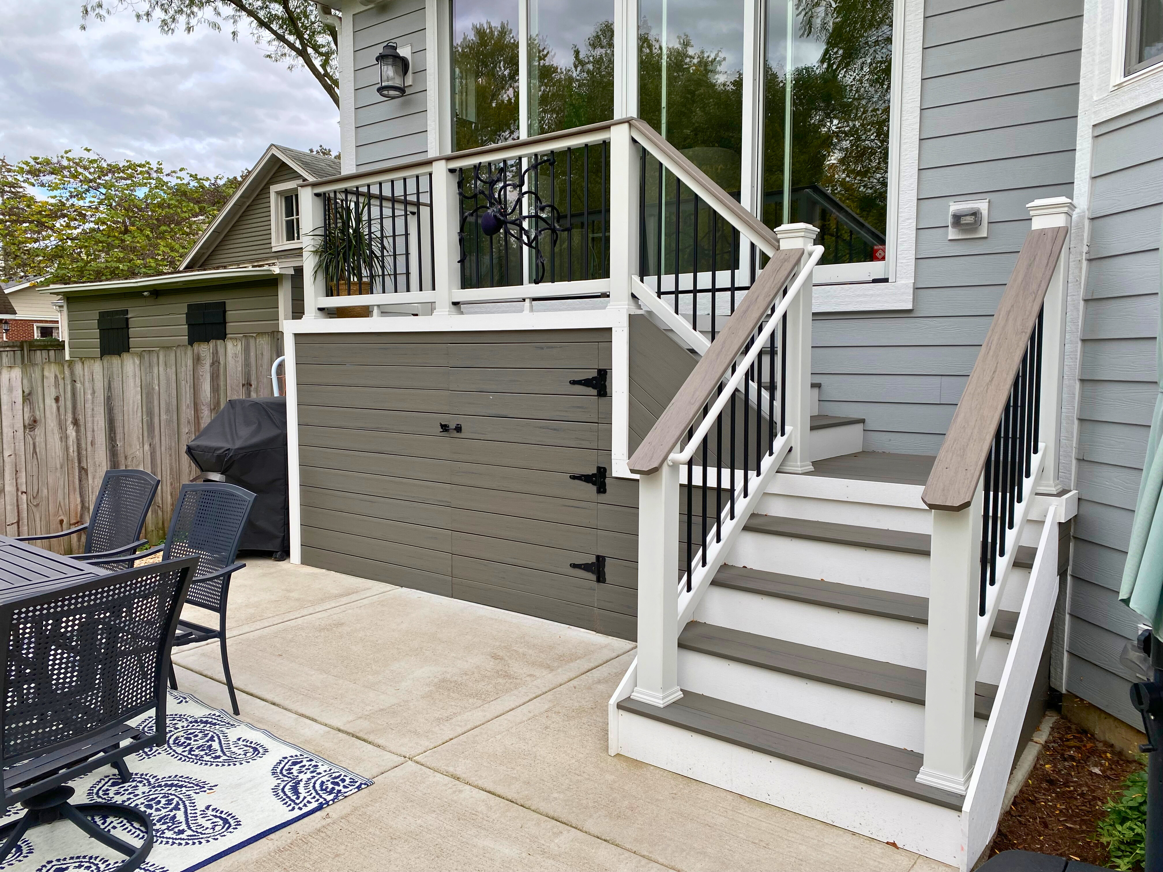 Large composite deck in Wheaton, IL with light brown decking, white railing posts, and black balusters. Overhead view of a spacious deck with outdoor dining furniture.