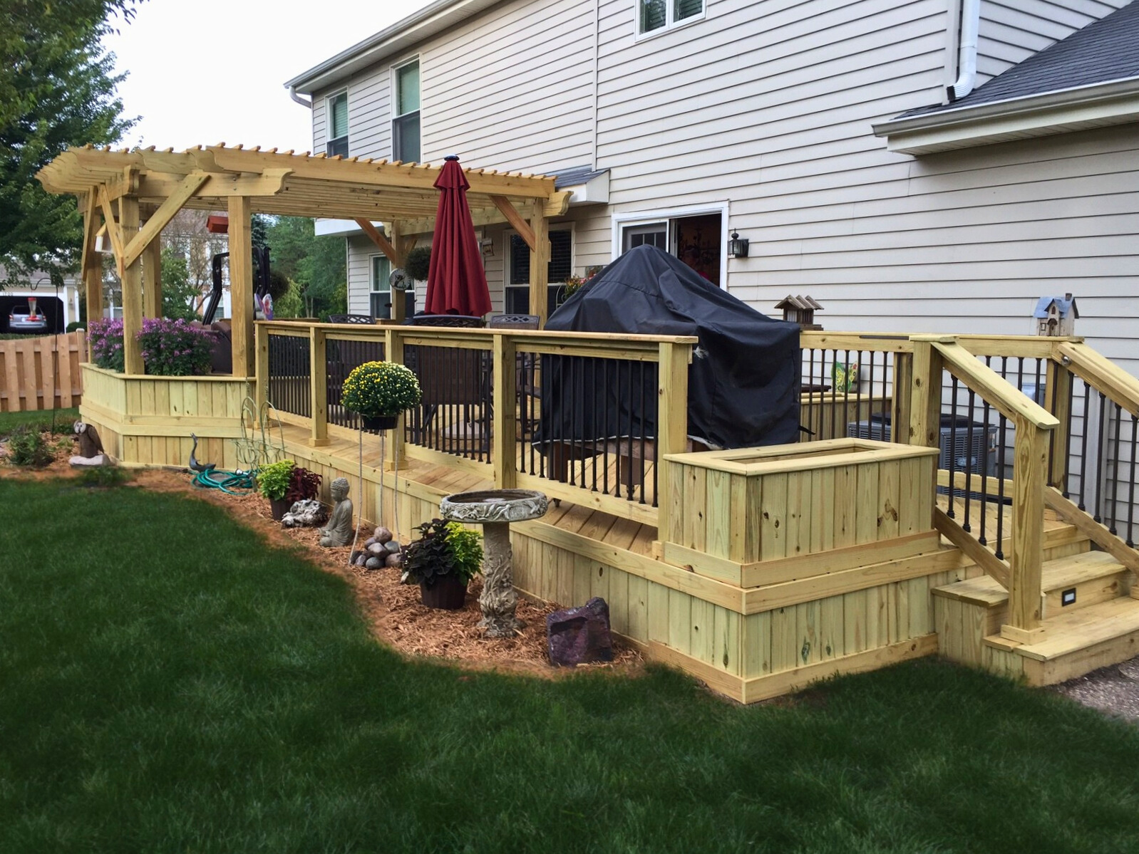 Custom wood deck with a pergola, black balusters, and planter boxes in a Libertyville IL backyard.
