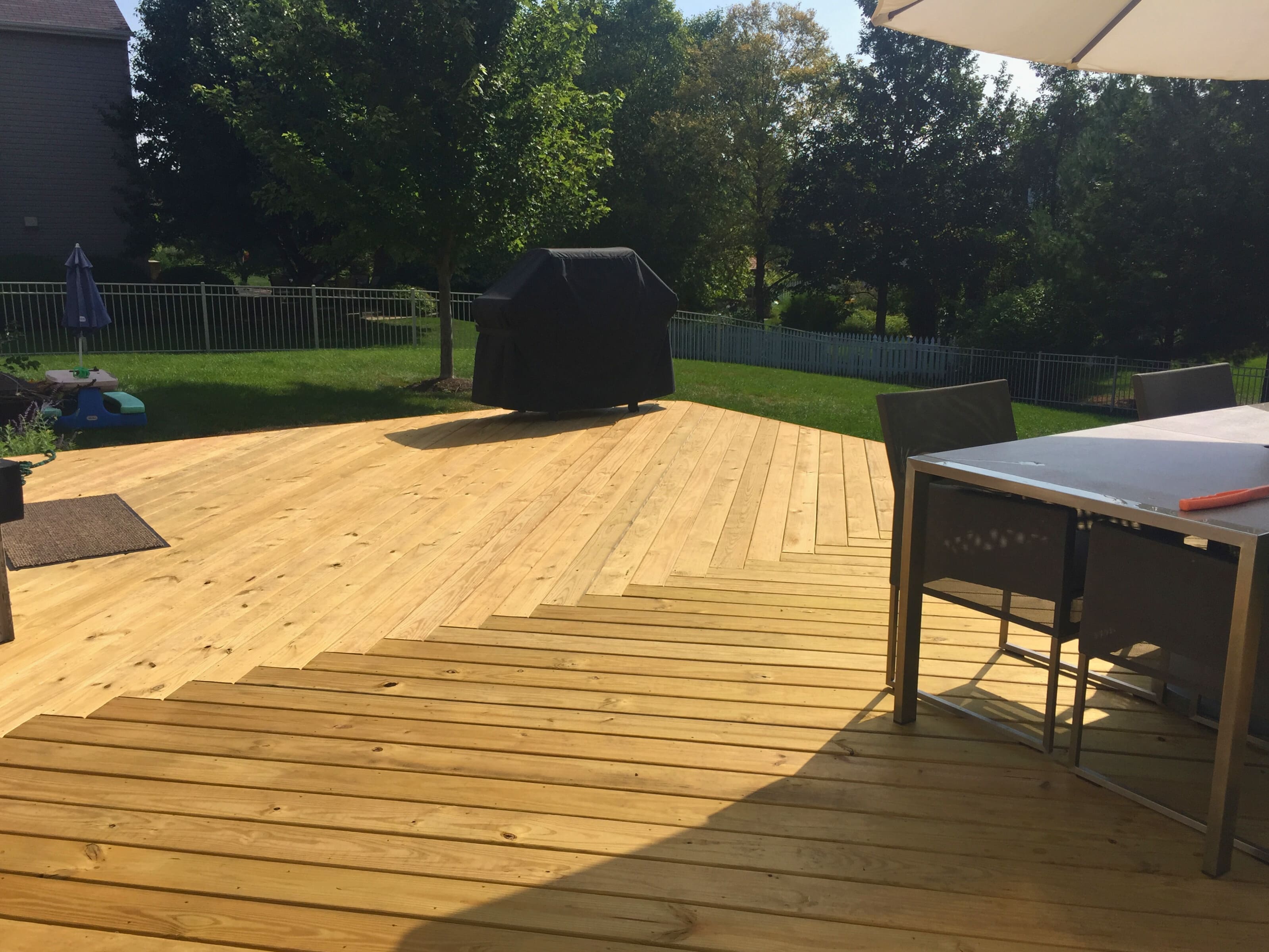 Large, newly built light-colored wood deck with an outdoor dining table and grill, extending from a house in St. Charles, IL.