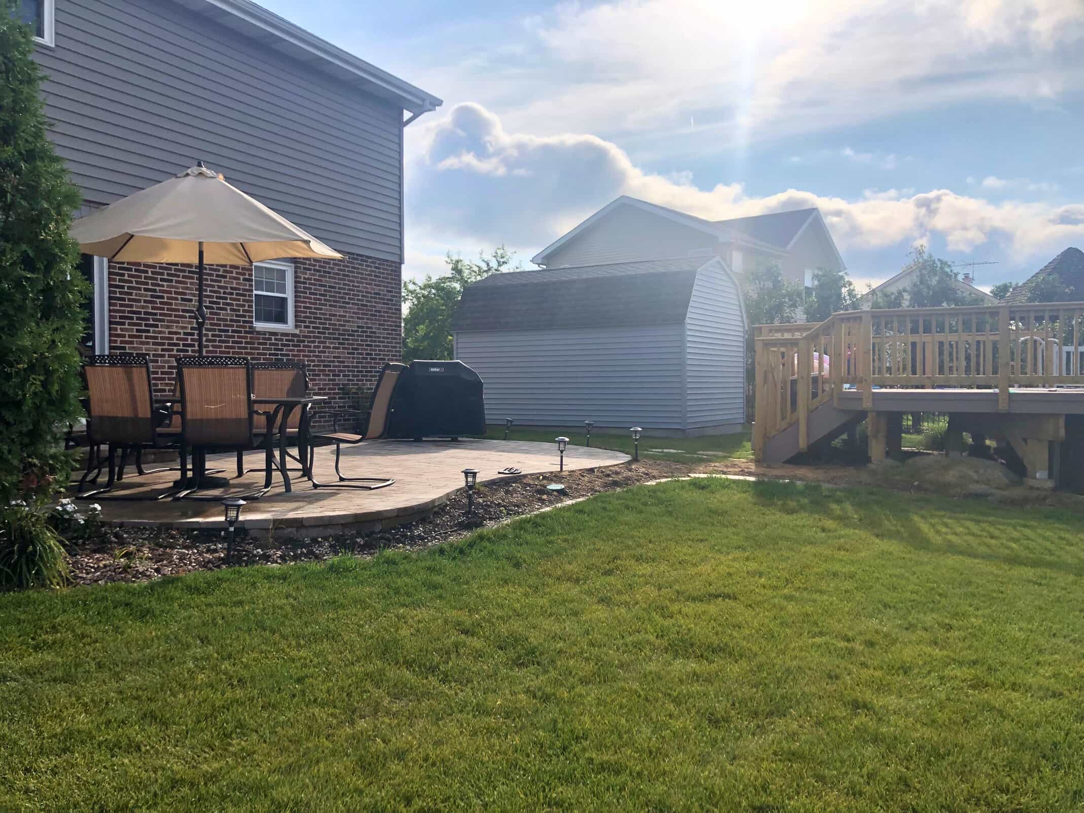 Backyard scene with a paver patio and an elevated wood deck in Frankfort, IL