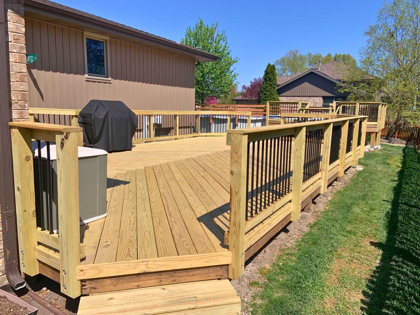 Expansive wooden deck with black metal balusters and built-in amenities for a Frankfort, IL home