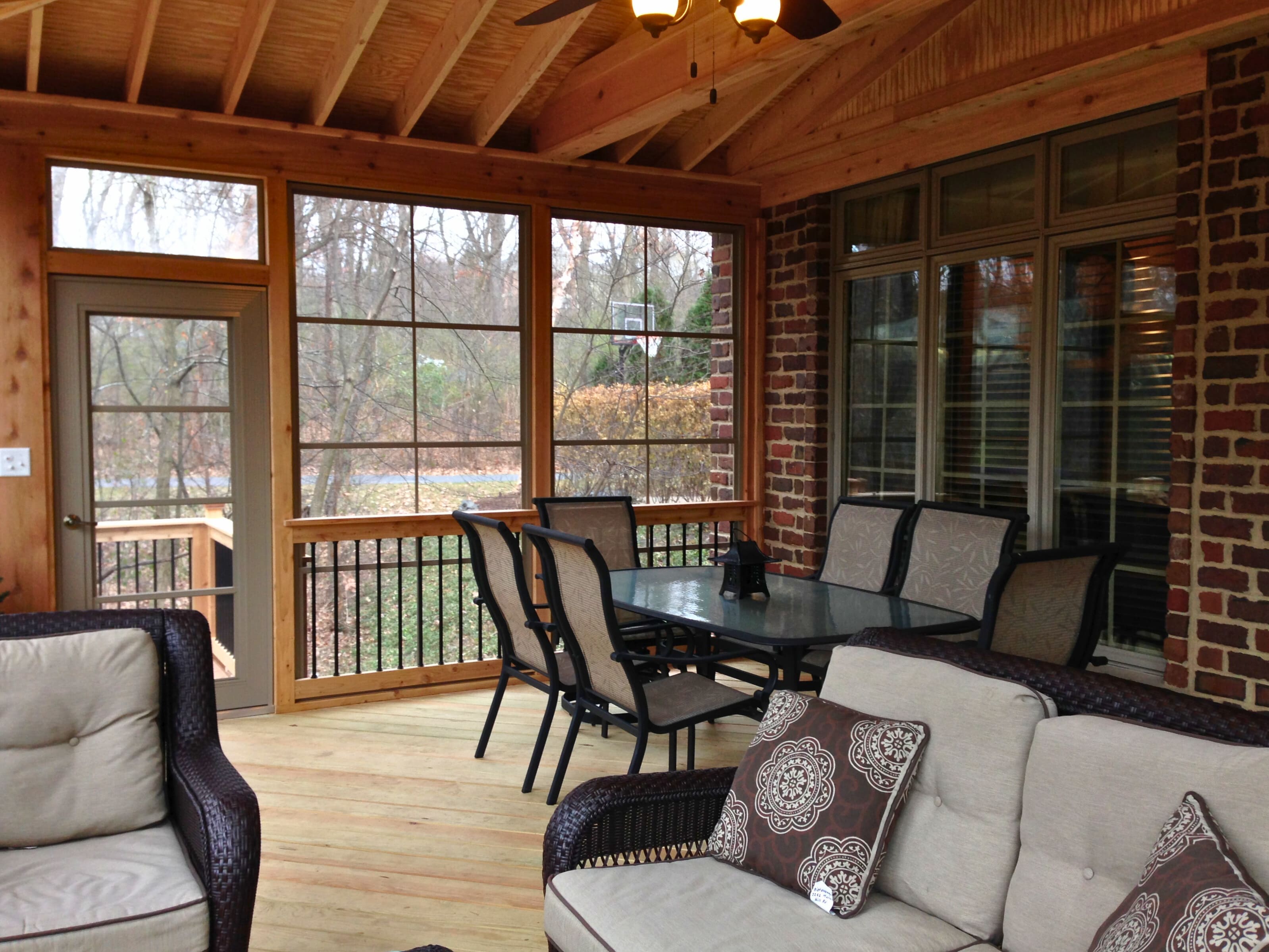 Interior of a screened porch in St. Charles, IL, with a vaulted wooden ceiling, exposed rafters, and comfortable outdoor seating around a table.