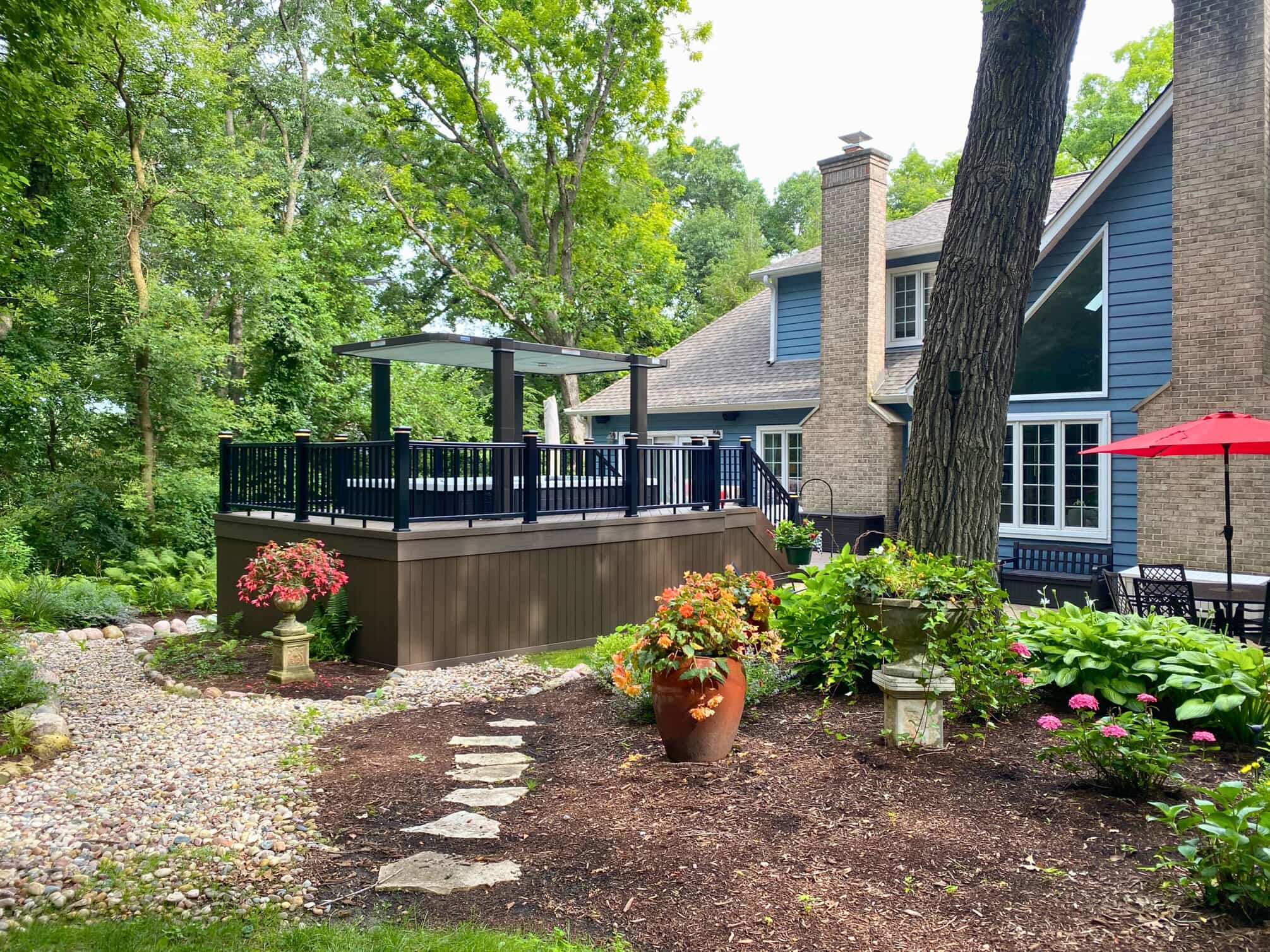 Modern composite deck in St. Charles, IL, with black railings, an integrated hot tub under a contemporary canopy, and extensive green landscaping.