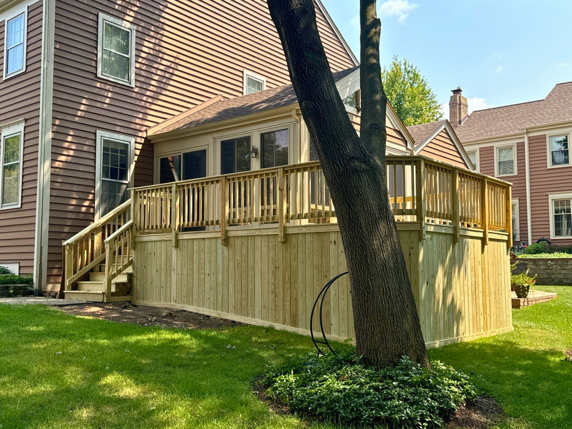 An expansive composite deck provides ample space for outdoor entertaining and relaxation at this Wheaton residence, featuring warm brown decking and crisp white railings.