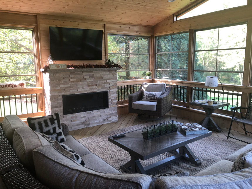 A cozy Chicagoland porch with wicker furniture, a colorful rug, and large windows.