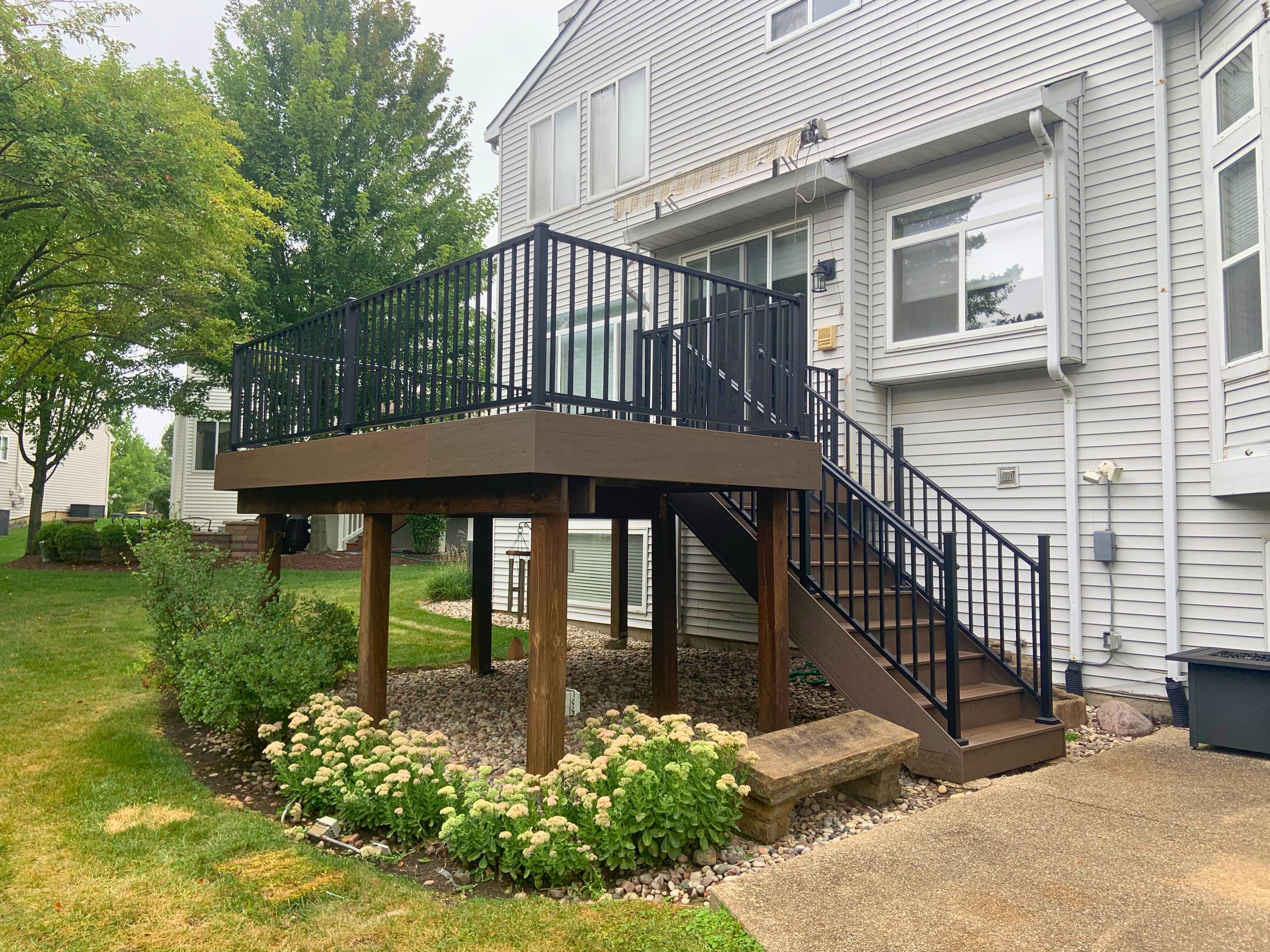 An elevated composite deck featuring dark brown decking and black railings, built by a composite deck builder in Woodridge.