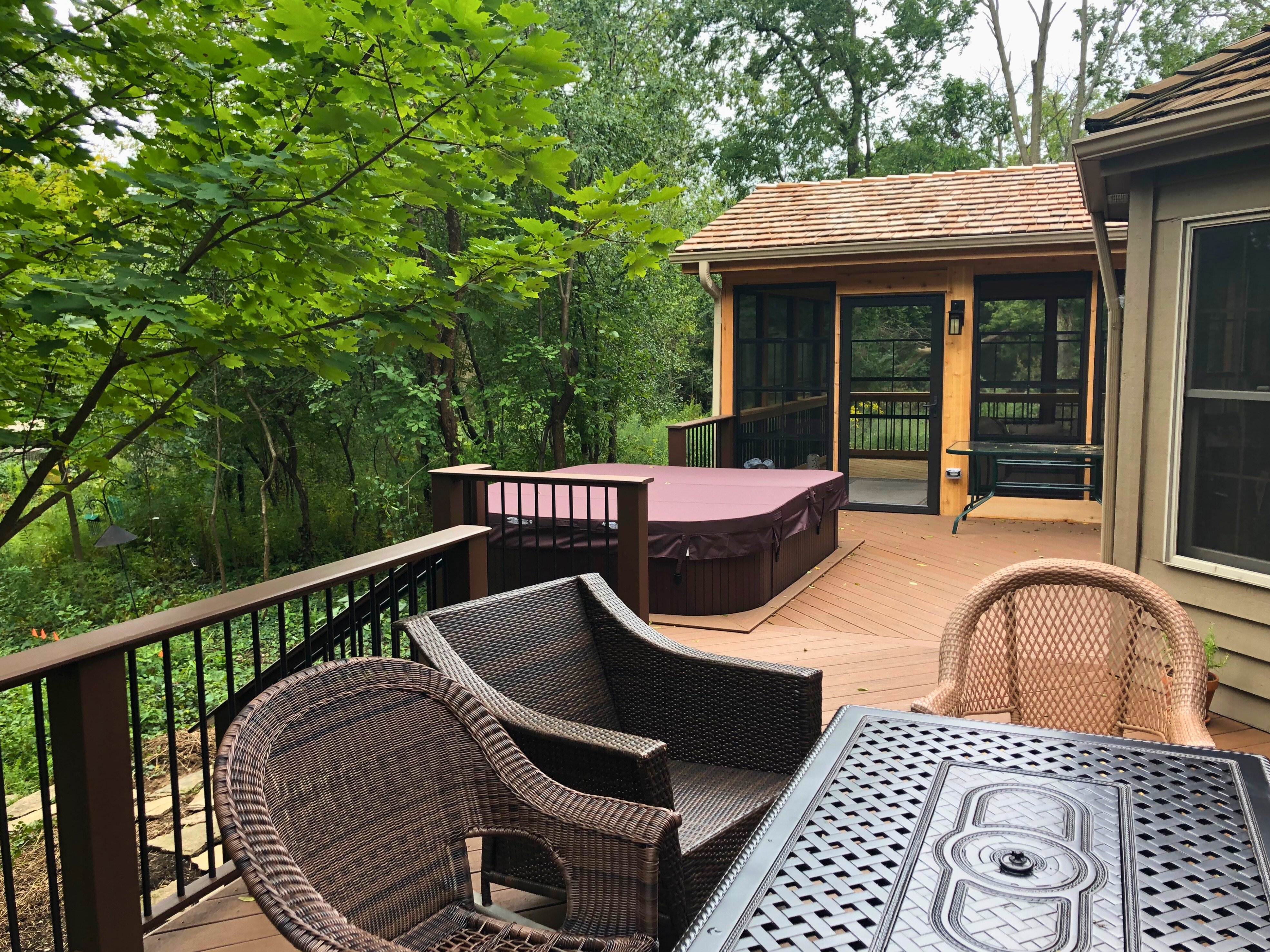 A custom TimberTech deck in Gurnee featuring an integrated hot tub and an attached screened-in sunroom, showcasing an outdoor living space built by Archadeck.