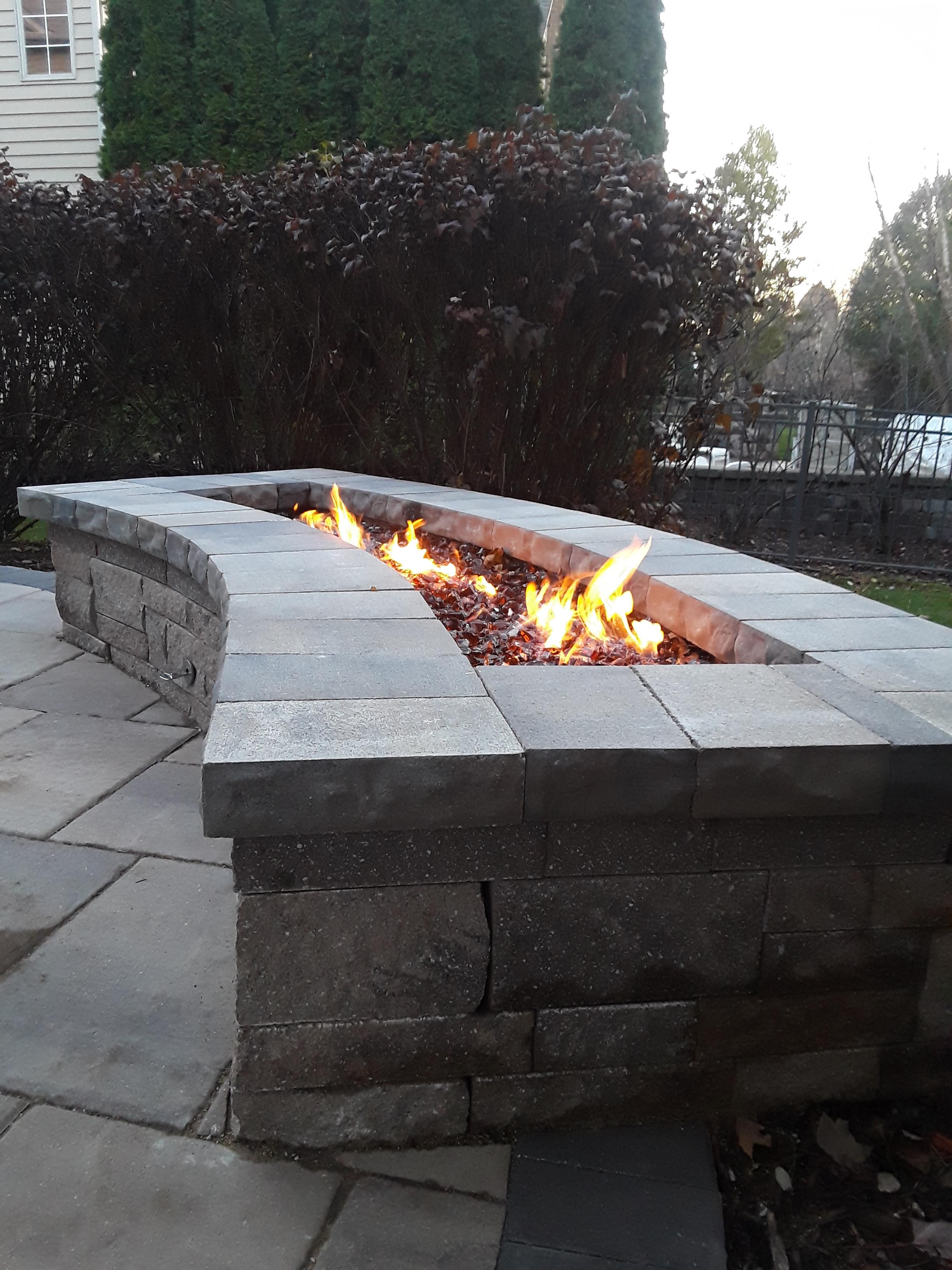 A long, rectangular custom fire pit made of stone pavers.
