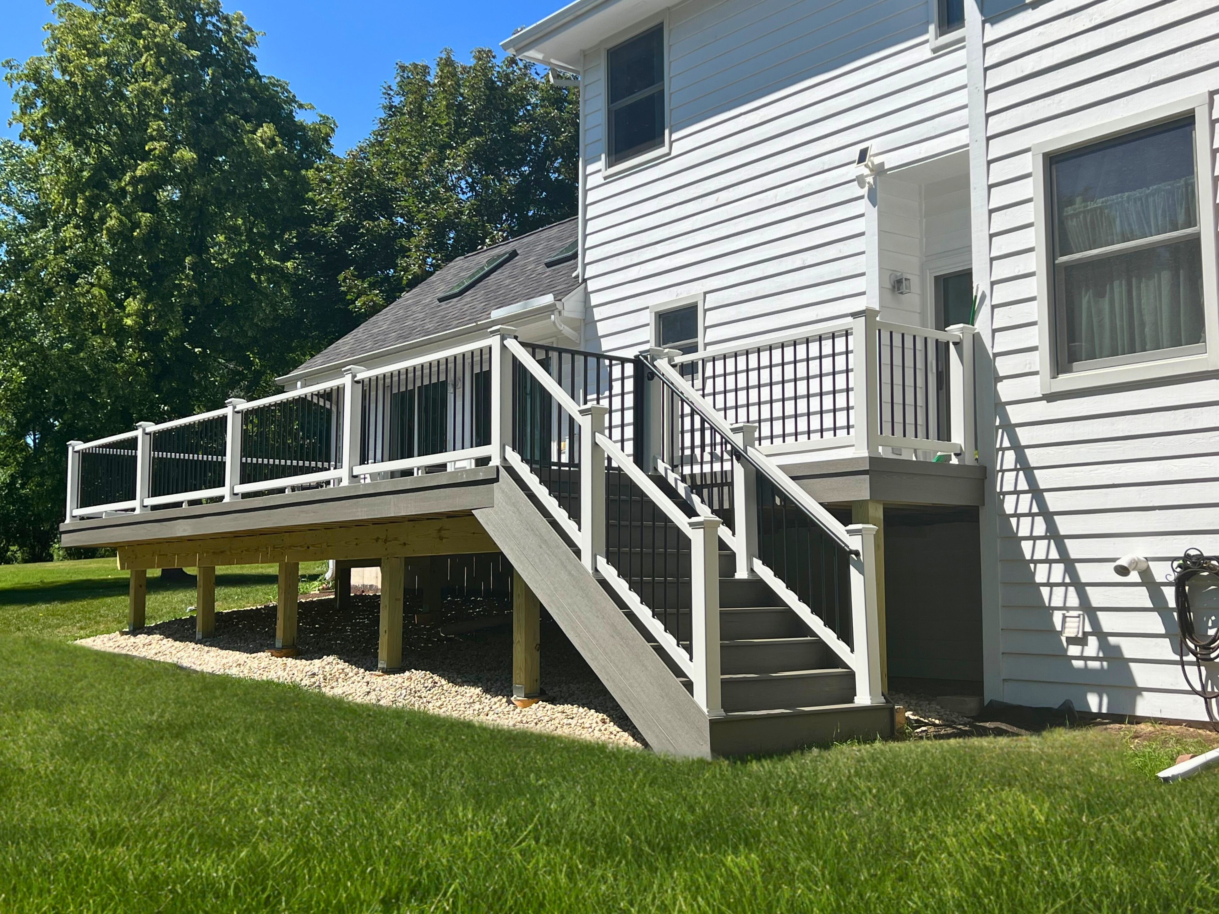 A custom TimberTech deck in Gurnee featuring an integrated hot tub and an attached screened-in sunroom, showcasing an outdoor living space built by Archadeck.