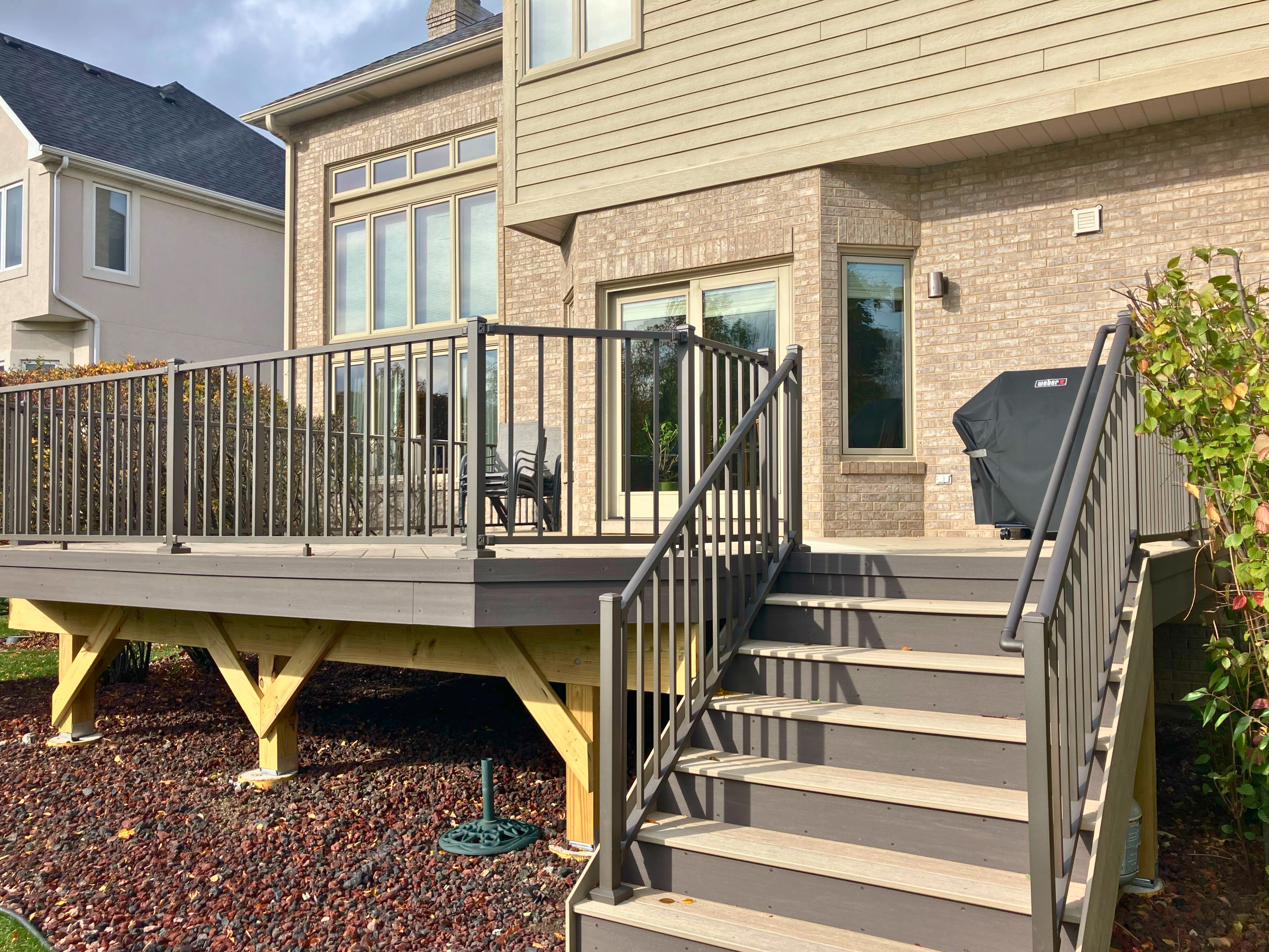 A new elevated composite deck with gray steps and railings, a project from a leading deck builder in Woodridge.