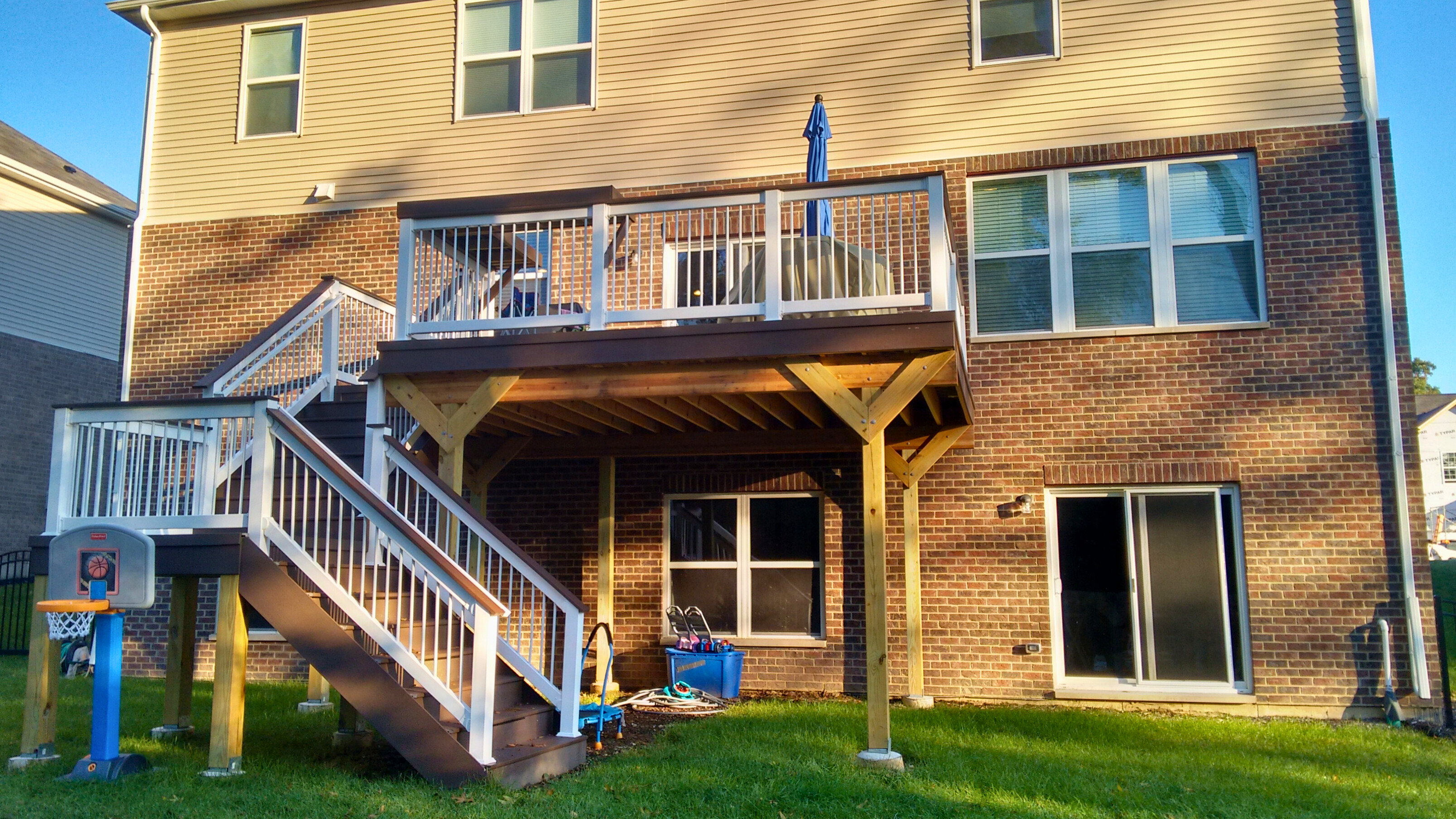 A completed residential deck with a white railing system and staircase, built by a professional Woodridge deck builder.