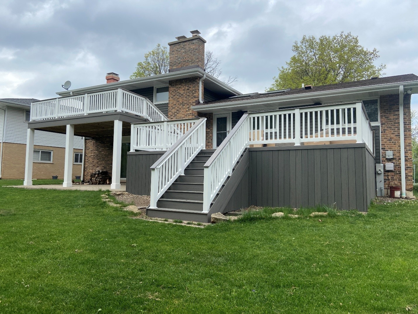 grey deck with stairs on the back of a brick house