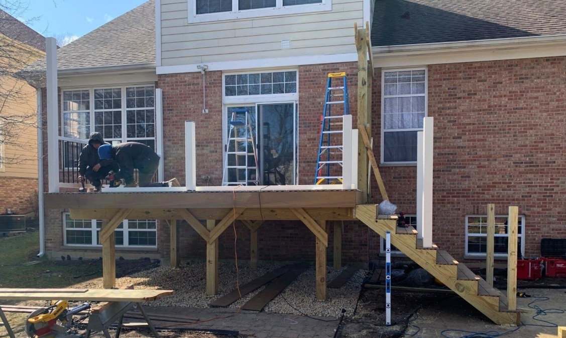 a group of men building a deck on the back of a brick house