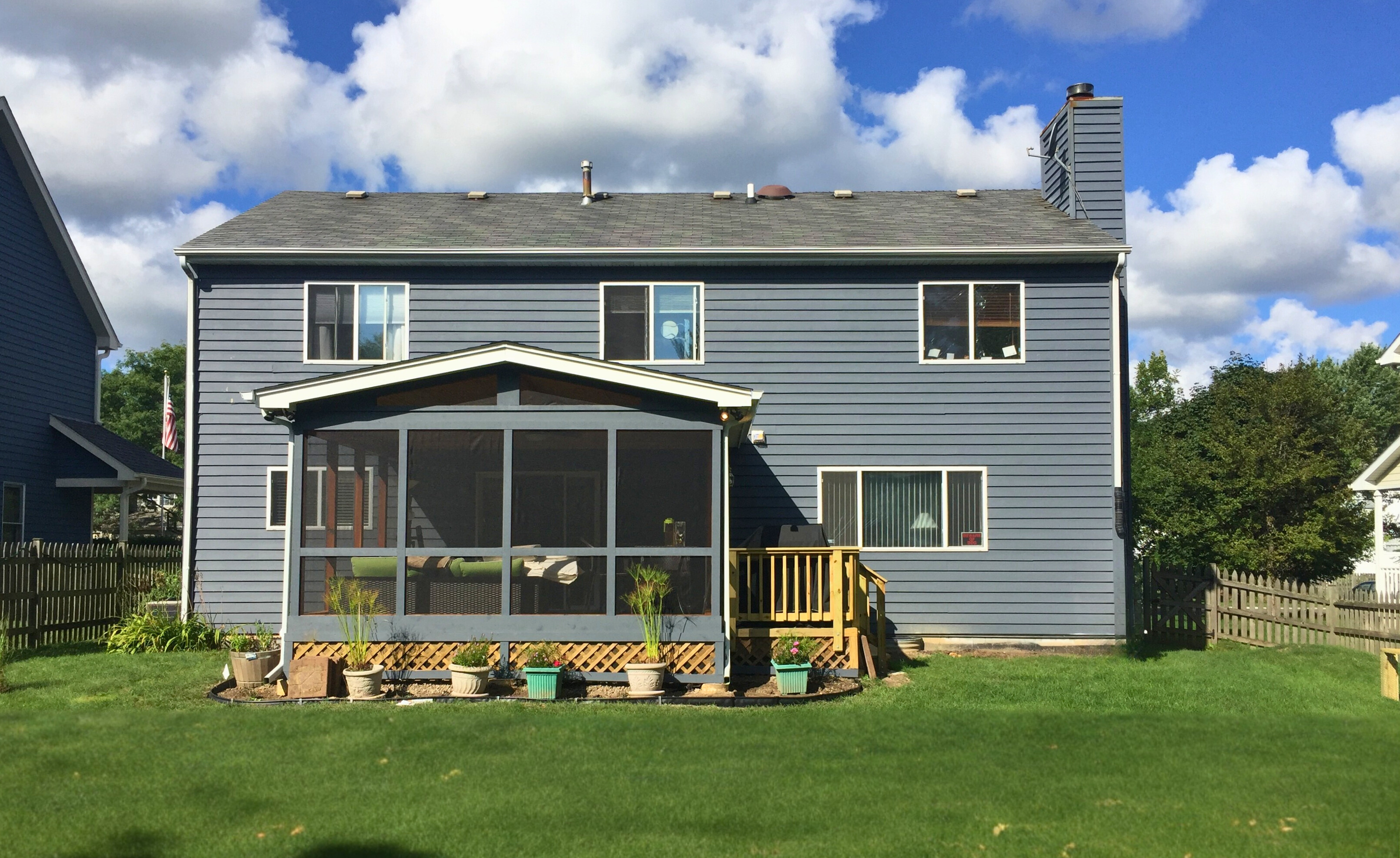 Exterior view of a newly constructed screened porch addition on a blue house in Gurnee, expanding the home's outdoor living area.