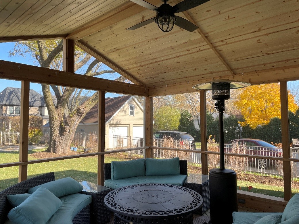 A wood-paneled screened porch with outdoor furniture.