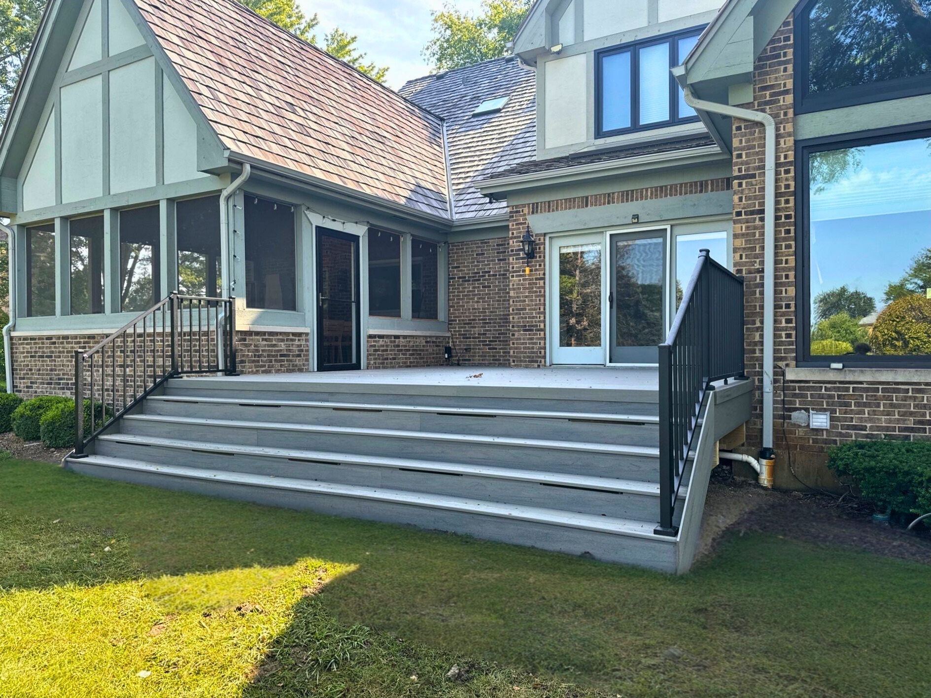 Composite deck with light grey boards and black metal railing, adjacent to a house with large windows, Barrington, IL.
