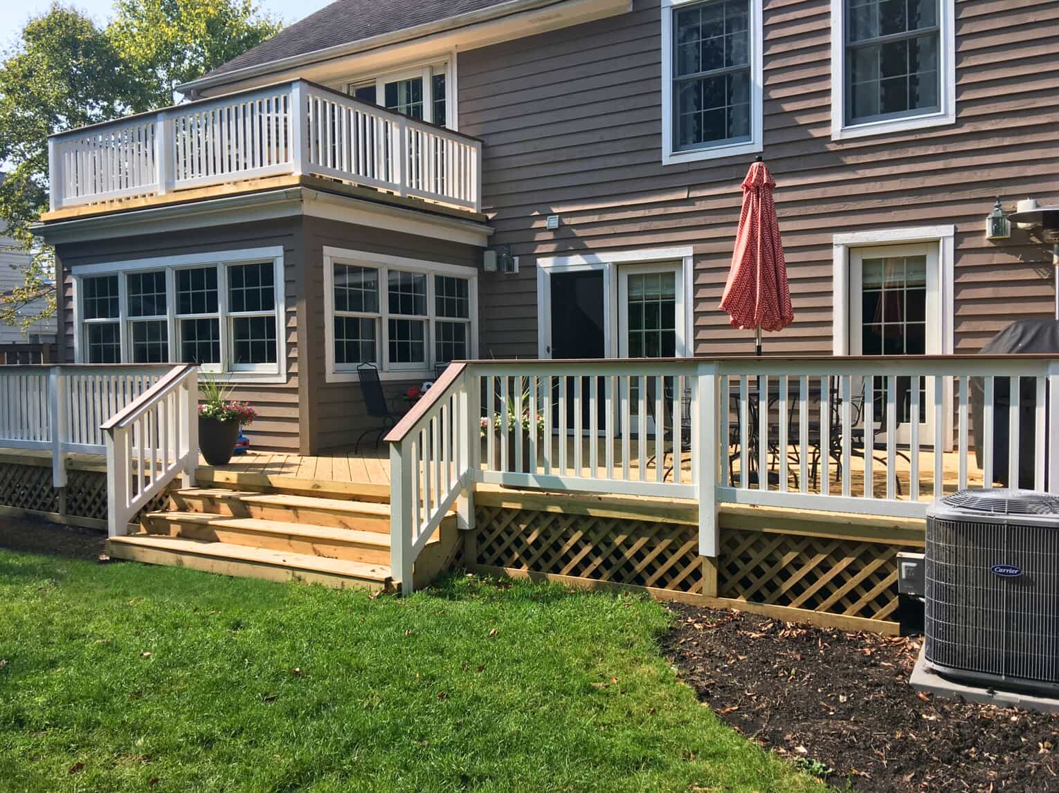 Large two-story composite deck with white railings and lattice skirting on a Highland Park home