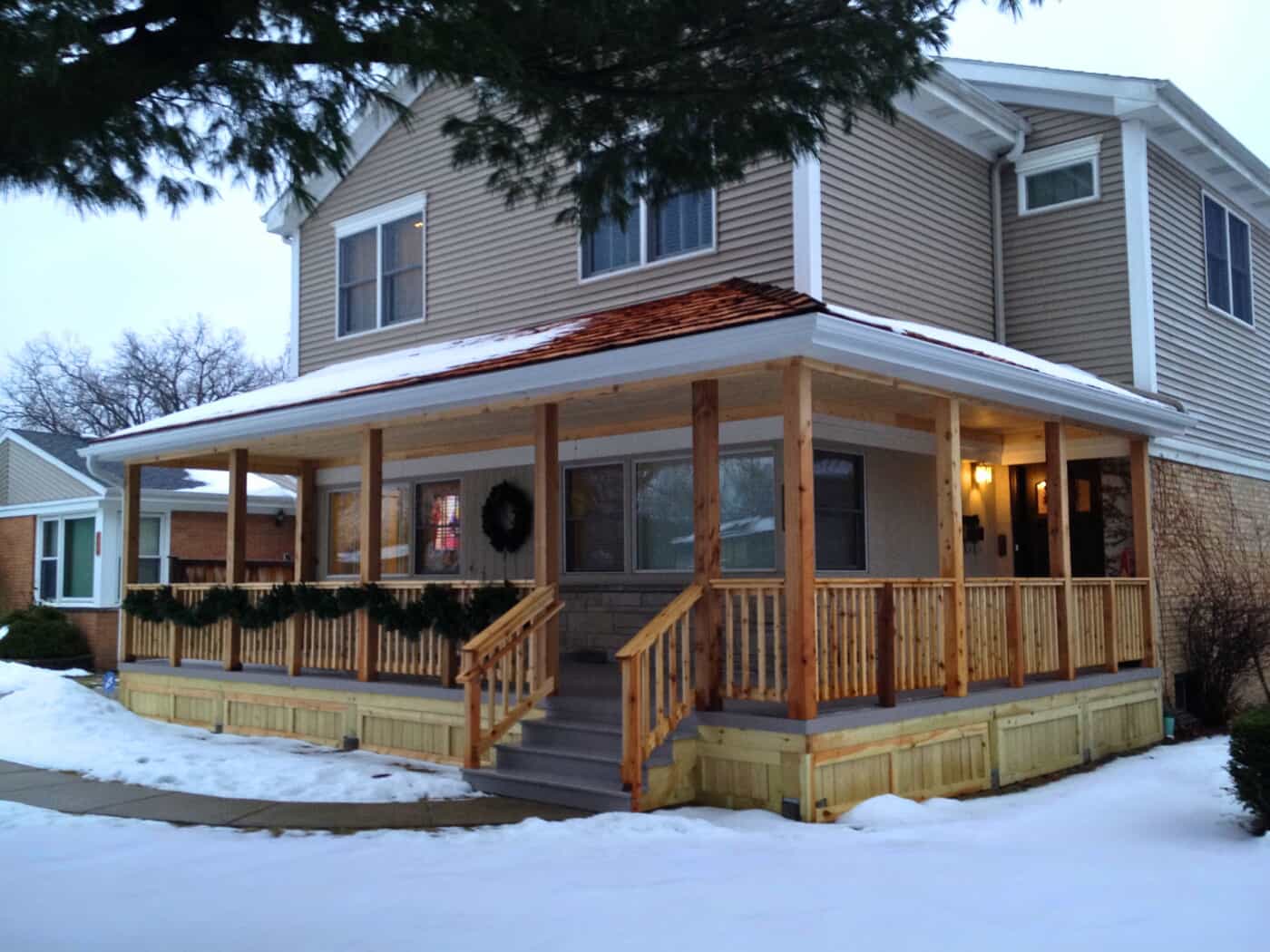 New wooden front porch with festive garland and steps on a Highland Park home in winter