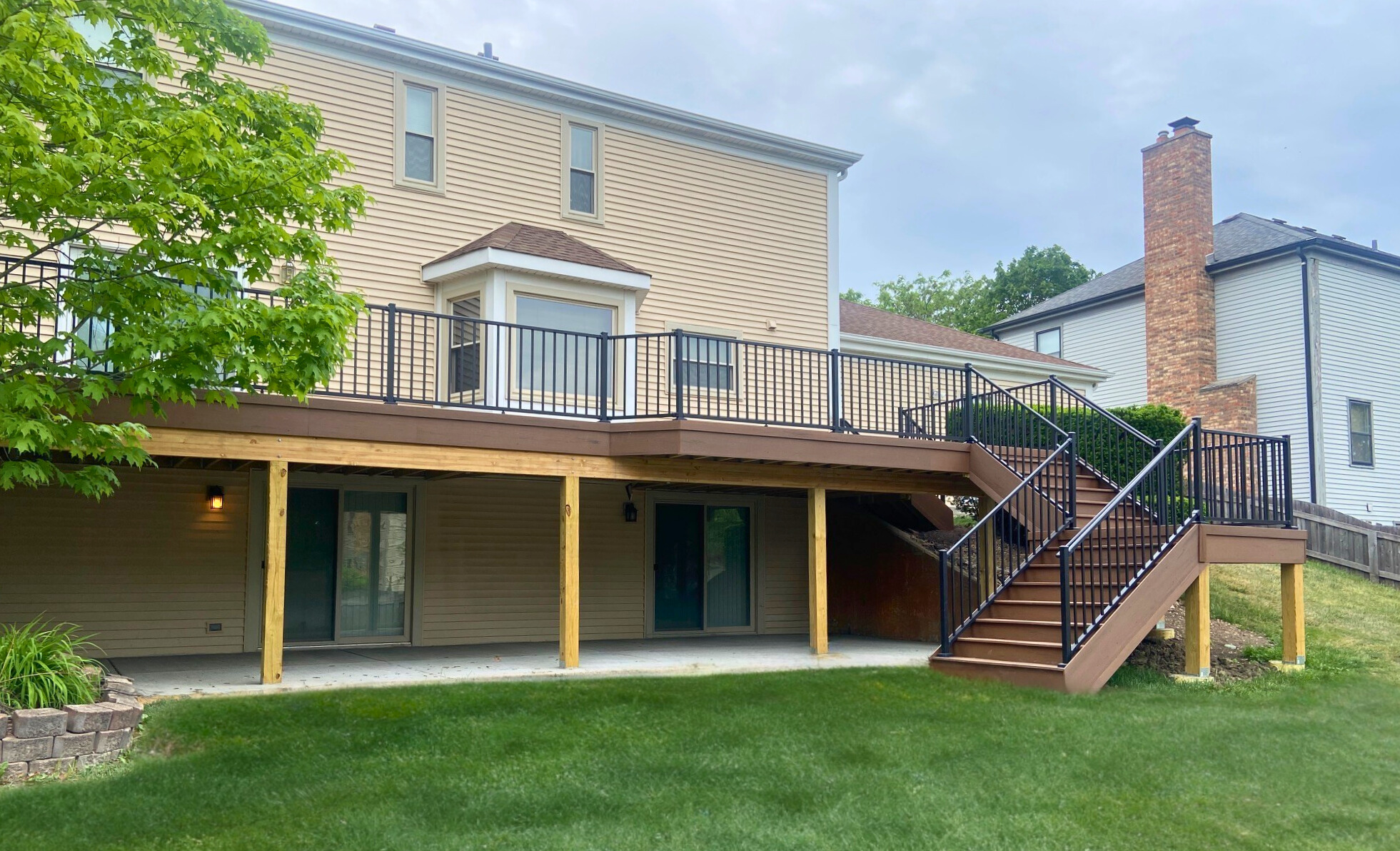 Multi-level composite deck with black aluminum railing and stairs by Archadeck of Chicagoland in Hoffman Estates.