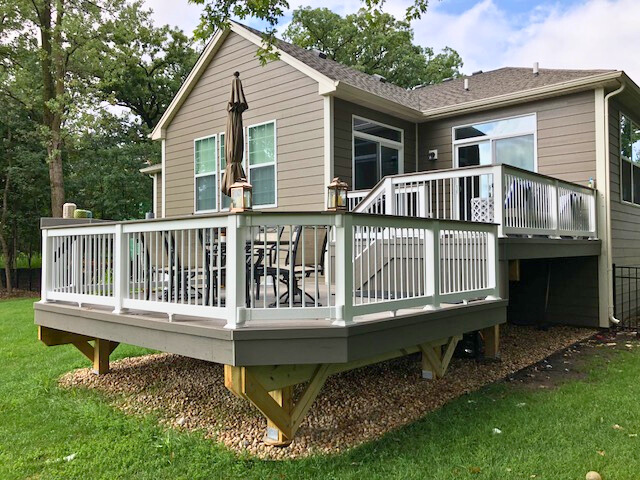 Elevated pressure-treated wood deck with black metal balusters and stairs leading to a backyard in Hoffman Estates.