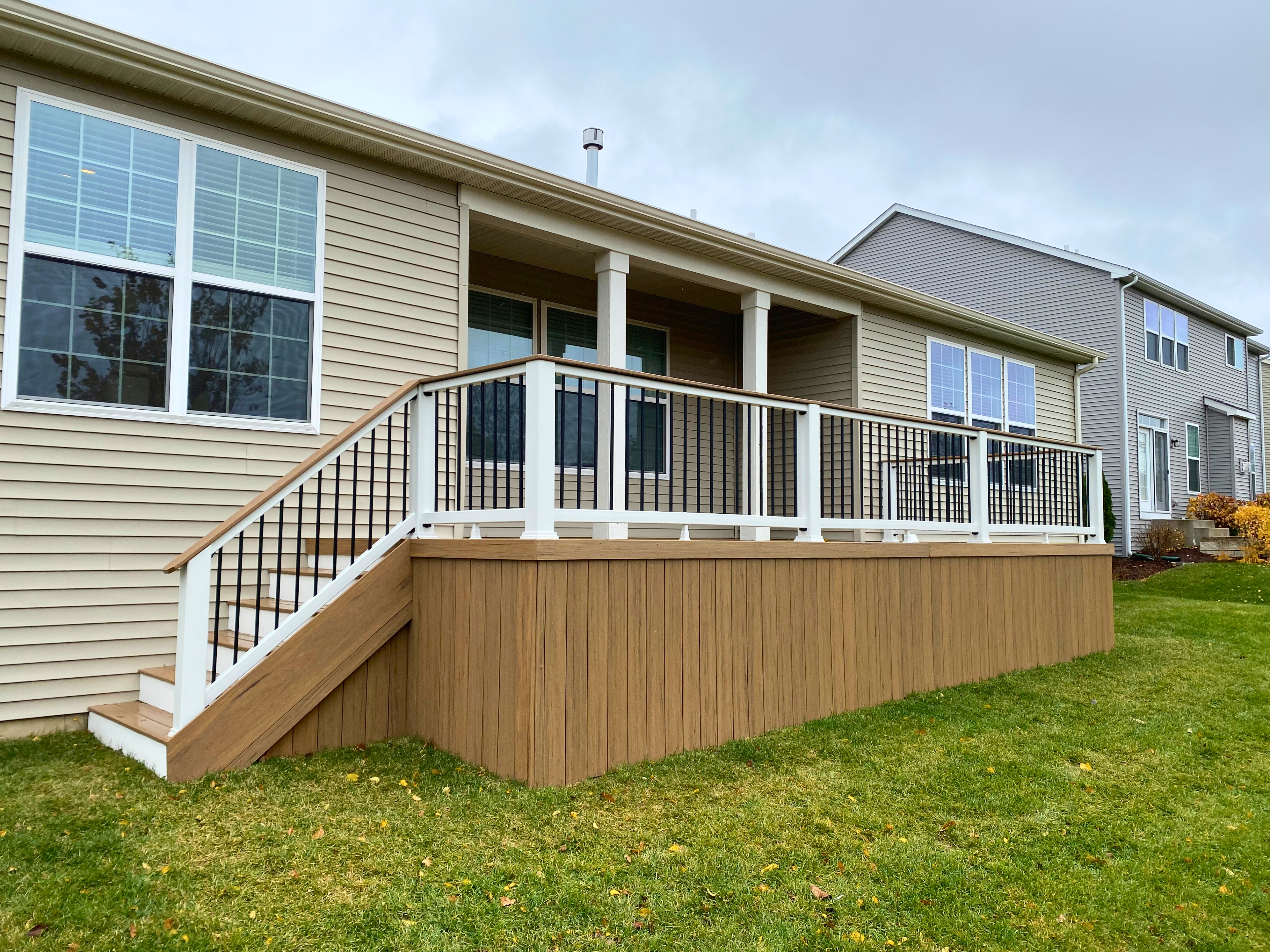 Expansive wooden deck with lattice skirting and a connected paver patio in a Hoffman Estates backyard.