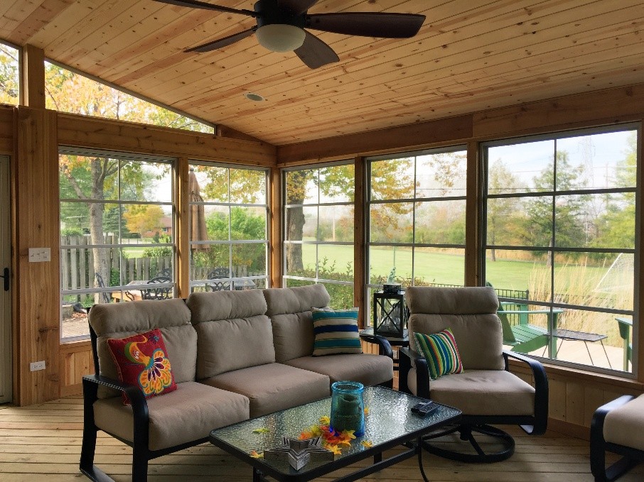  A two-story house with a newly built deck. The deck features a brown composite deck surface and black railings, with stairs leading down to a paved patio area.