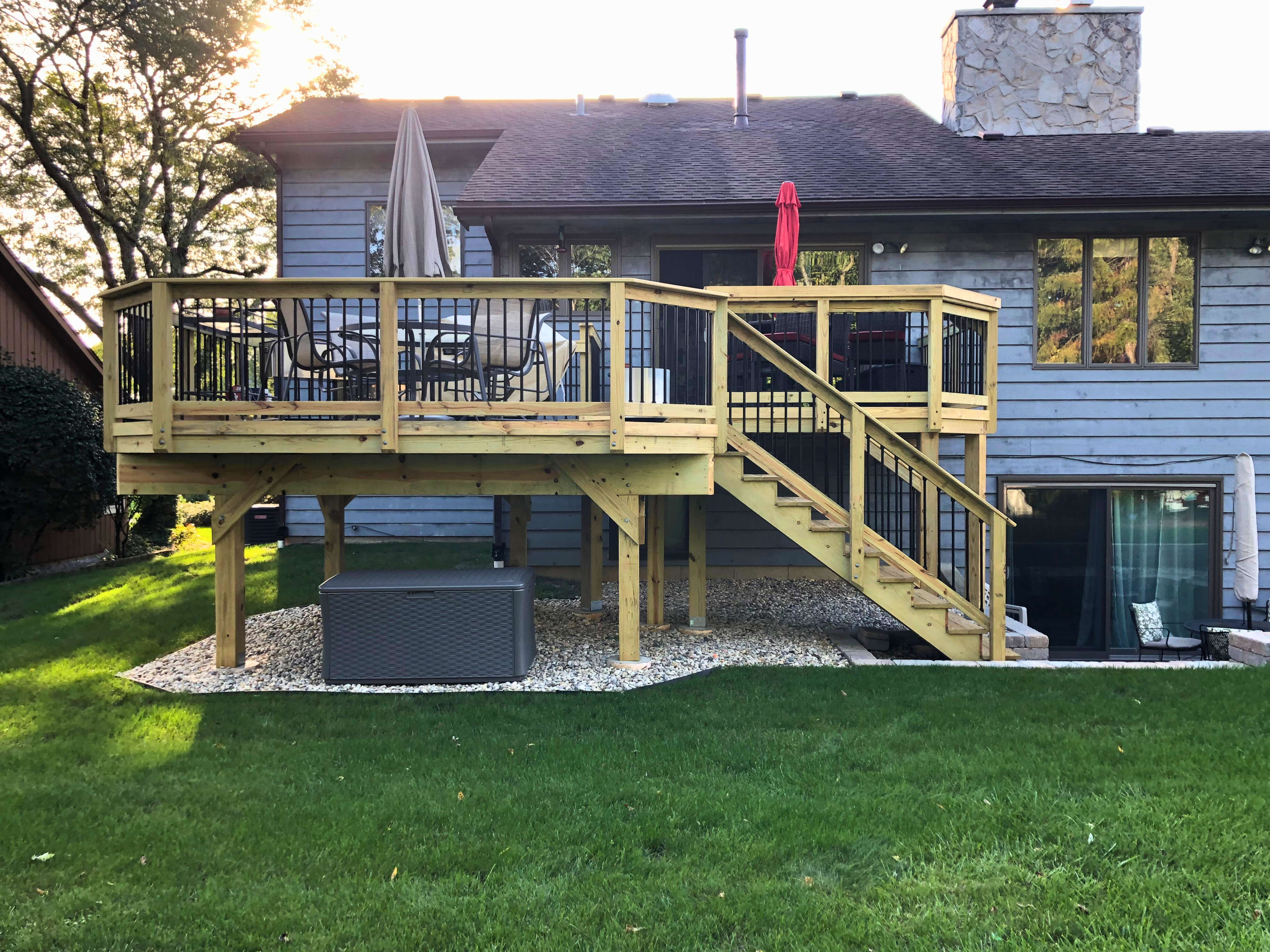 Multi-level wooden deck in Gurnee with black railings and steps leading to a walkout basement, designed for outdoor dining and relaxation.