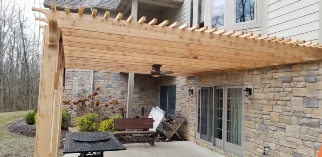 Wood pergola with ceiling fan over patio