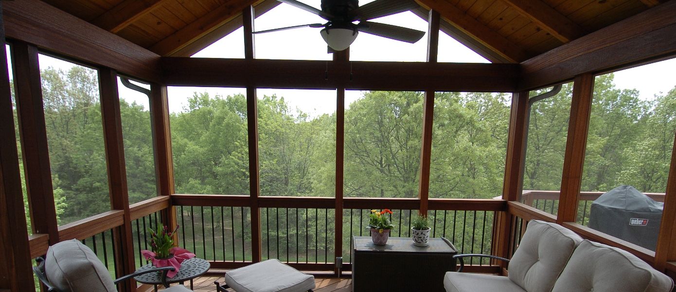 Furnished sunroom deck looking out onto trees.