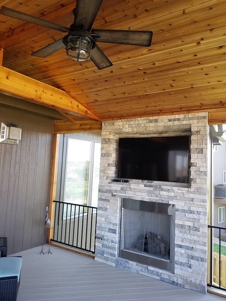 Outdoor fireplace and flat TV on screened porch