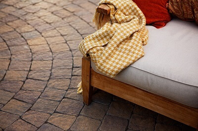 edge of couch with a yellow blanket hanging from it, showcasing patio floor