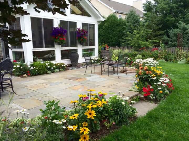 outside of a sunroom with patio and lots of flowers