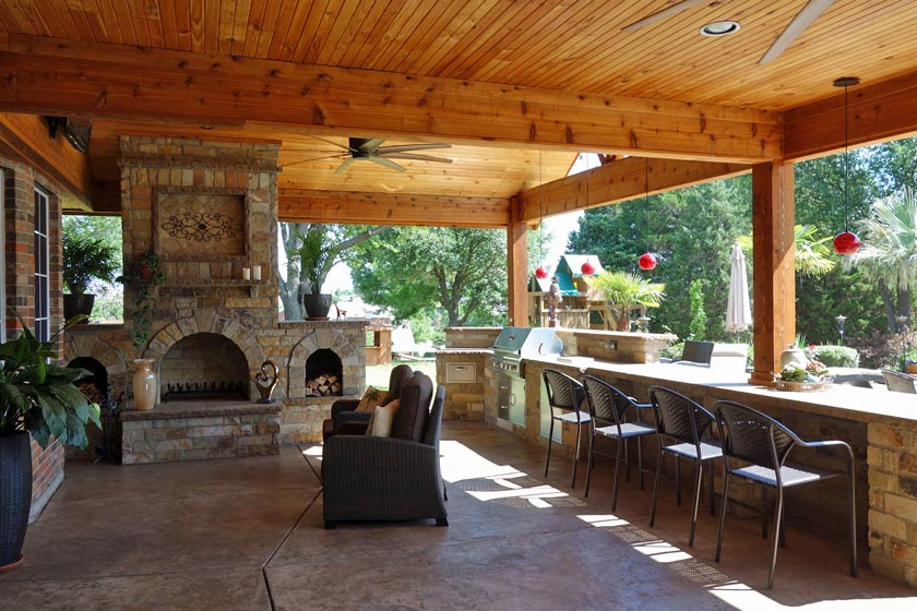 Covered patio area with outdoor kitchen, bar and fireplace