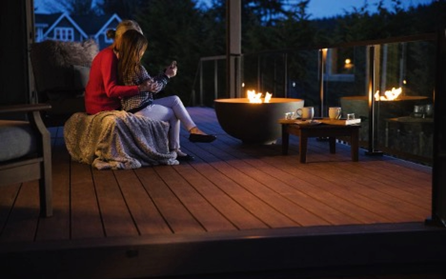 A couple sitting on a deck with a fire pit

Description automatically generated