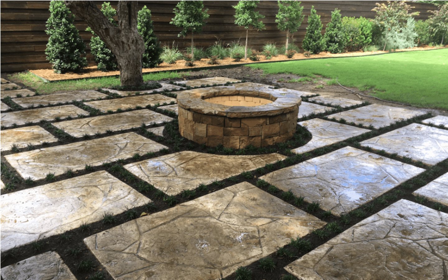 A stone patio with a fire pit

Description automatically generated